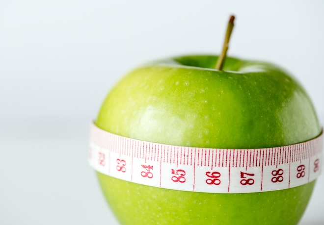 green apple with measuring tape wrapped around the middle